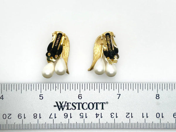 These elegant vintage clip-on Kramer earrings flow with understated grace, their brushed gold-tone leaves cradling luminous teardrop faux pearls.