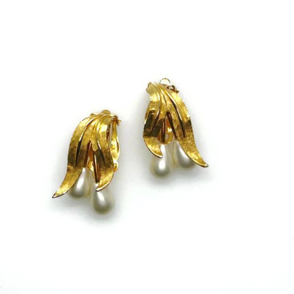 These elegant vintage clip-on Kramer earrings flow with understated grace, their brushed gold-tone leaves cradling luminous teardrop faux pearls.