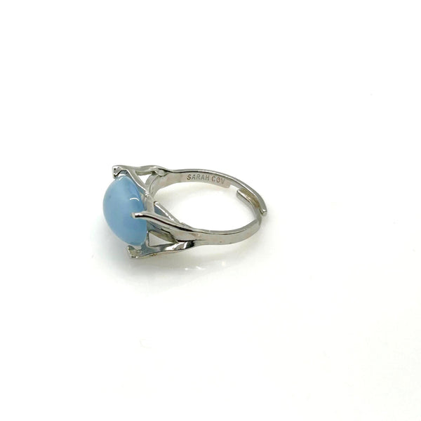 Minimalist silver statement ring with a prominent, opaque sky-blue oval stone cabochon centered on a polished silver tone adjustable band marked Sarah Cov.