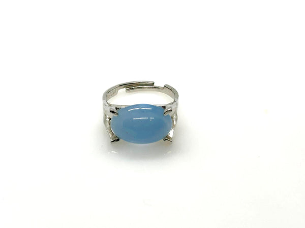 Minimalist silver statement ring with a prominent, opaque sky-blue oval stone cabochon centered on a polished silver tone adjustable band marked Sarah Cov.