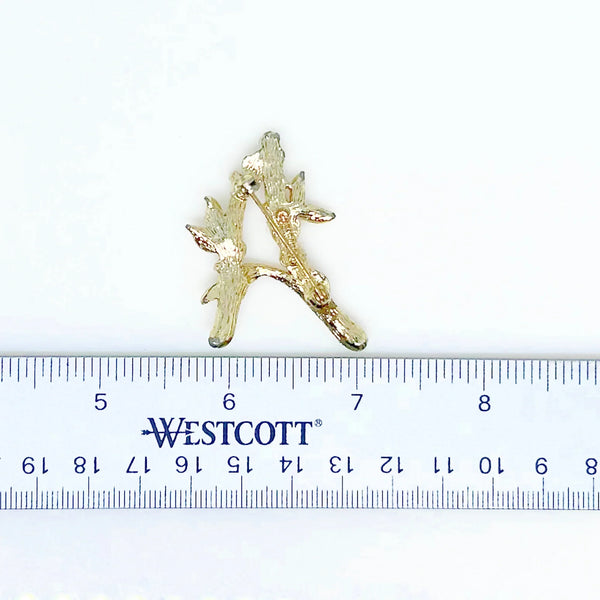 Discover timeless charm with the Sarah Coventry Initial "A" Vintage Brooch, a classic accessory that adds a personalized touch to any outfit. This elegant brooch, originating from 1964, offers a unique design created from golden metal with a texture resembling bamboo or tree bark, making it a standout piece for collectors and fashion enthusiasts alike.