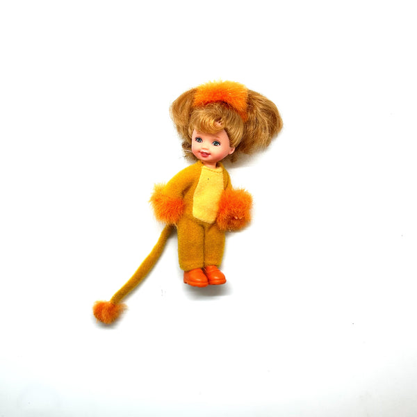 Vintage 2000 Mattel Kelly Club Lion Liana doll in a plush yellow and orange lion costume. The miniature blonde Barbie friend doll features fuzzy wrist cuffs, matching orange boots, and a long tufted tail against a solid white background