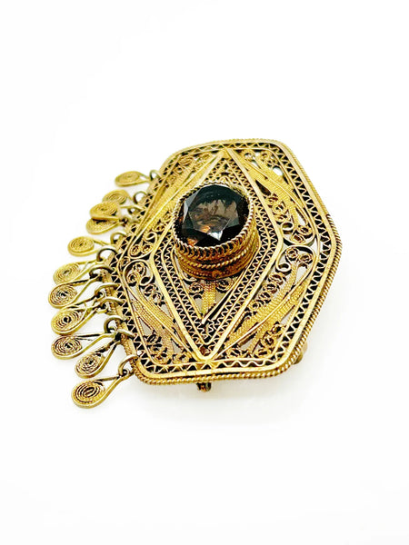 Vintage Israel Filigree Brooch/pendant with Tassels and Smokey Quartz center Stone.It has a geometric shape with tiny filigree drops at the bottom, and a large, faceted oval stone is the centerpiece. The metal is extremely intricate and detailed, both front and back.