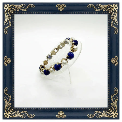 This exquisite vintage bracelet combines timeless elegance with striking visual appeal. Featuring alternating domed lapis-style stones in rich deep blue tones paired with lustrous faux pearls, all set in warm gold-tone metal, it's a statement piece that elevates any ensemble.