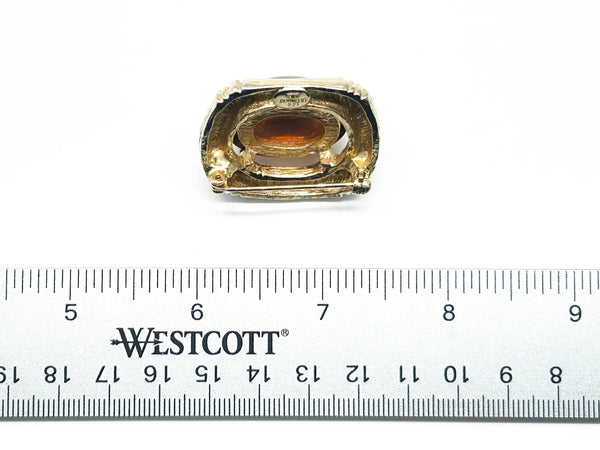 Indulge in the warm, honeyed glow of this delightful Les Bernard brooch. Rich amber glass catches the light like liquid caramel, nestled within a brushed gold-tone squared setting that frames it to perfection.