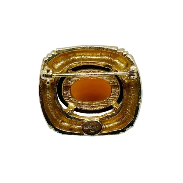 Indulge in the warm, honeyed glow of this delightful Les Bernard brooch. Rich amber glass catches the light like liquid caramel, nestled within a brushed gold-tone squared setting that frames it to perfection.