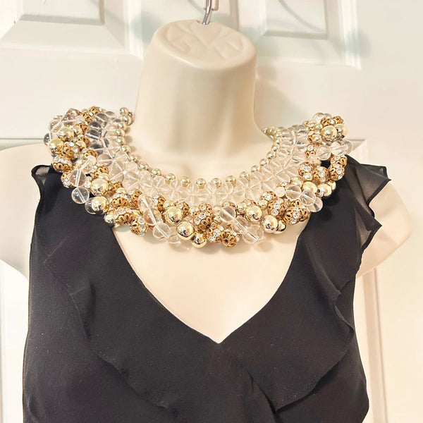 Add a touch of glamour to your wardrobe with this one-of-a-kind statement piece. Crafted with heavy glass and gold beads, this collar necklace boasts intricate rows of round gold beads, graduated clear beads, and rhinestone-studded rondelles for an eye-catching effect.
