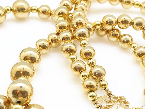 Striking and Dramatic, this gold bead double strand necklace is signed Marvella and measures 25” and 26" with a hook clasp, slight wear to clasp