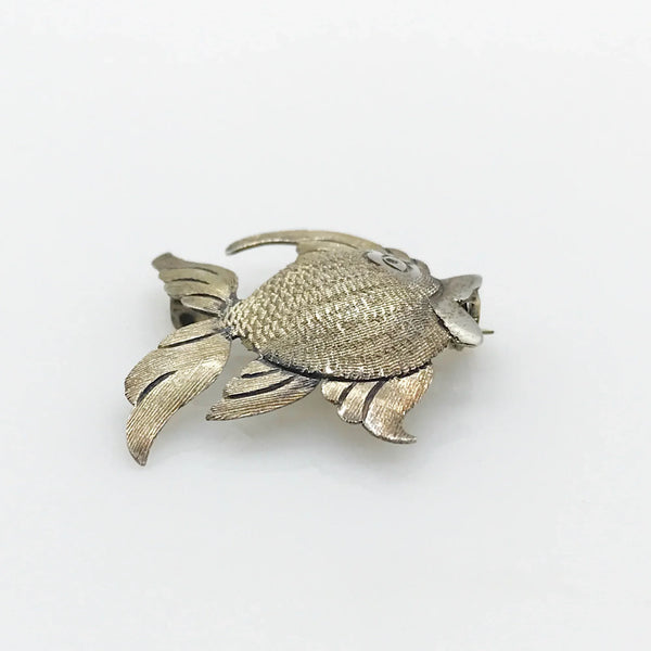 This is a whimsical brooch in the shape of a fish. The detailing on the scales and fins is particularly nice. It measures 1.25” across. Add a touch of charm to any outfit with our Vintage Mexican Silver Fish Brooch. You'll love the intricate detailing on the scales and fins, giving it a unique and whimsical touch. At 1.25" across, it's the perfect size for everyday wear.