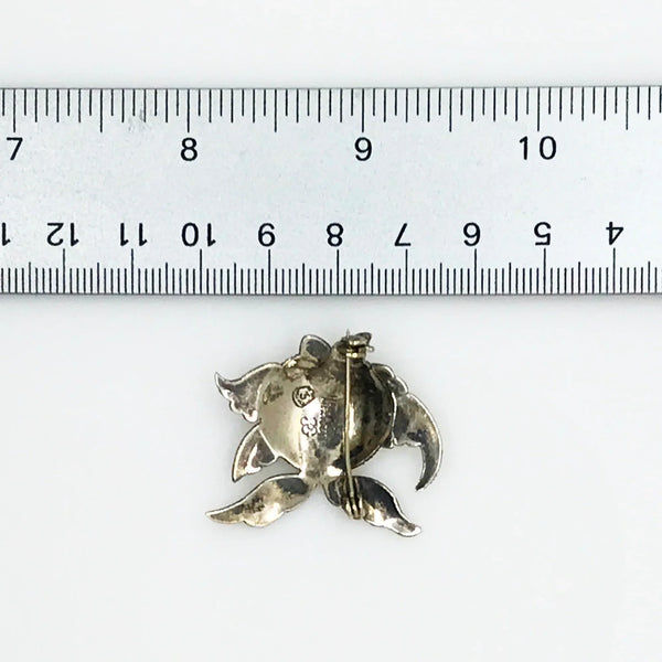 This is a whimsical brooch in the shape of a fish. The detailing on the scales and fins is particularly nice. It measures 1.25” across. Add a touch of charm to any outfit with our Vintage Mexican Silver Fish Brooch. You'll love the intricate detailing on the scales and fins, giving it a unique and whimsical touch. At 1.25" across, it's the perfect size for everyday wear.