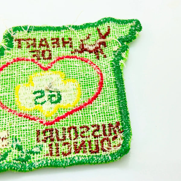 This authentic vintage shoulder patch celebrates the Heart of Missouri Girl Scout Council, once based in Jefferson City and Columbia. The distinctive Missouri-shaped design features a prominent pink heart showcasing the iconic Girl Scout "GS" logo at its center. 