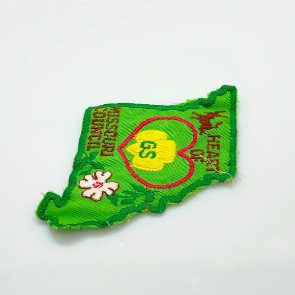 This authentic vintage shoulder patch celebrates the Heart of Missouri Girl Scout Council, once based in Jefferson City and Columbia. The distinctive Missouri-shaped design features a prominent pink heart showcasing the iconic Girl Scout "GS" logo at its center. 