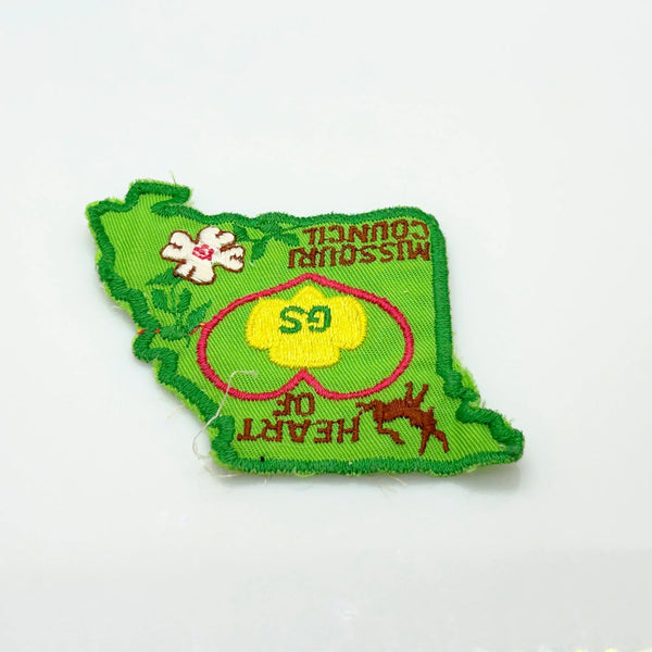 This authentic vintage shoulder patch celebrates the Heart of Missouri Girl Scout Council, once based in Jefferson City and Columbia. The distinctive Missouri-shaped design features a prominent pink heart showcasing the iconic Girl Scout "GS" logo at its center. 