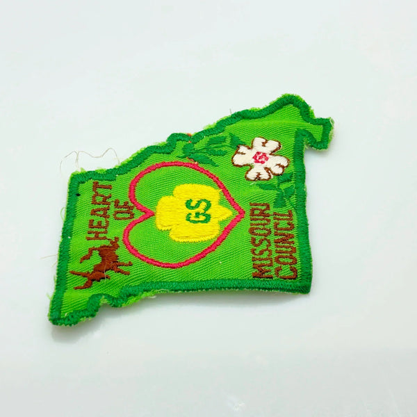 This authentic vintage shoulder patch celebrates the Heart of Missouri Girl Scout Council, once based in Jefferson City and Columbia. The distinctive Missouri-shaped design features a prominent pink heart showcasing the iconic Girl Scout "GS" logo at its center. 