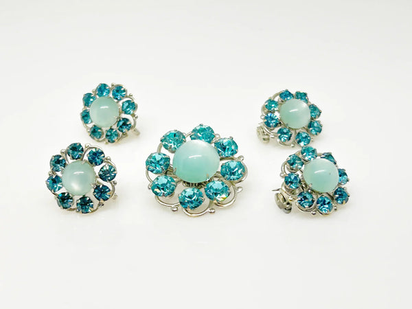 This is a hard to find set of a brooch, a pair of scatter pins, and screw back earrings. The design is round, frosted light turquoise cabochons.. The center moonglow stone is surrounded by bright faceted slightly deeper blue stones.