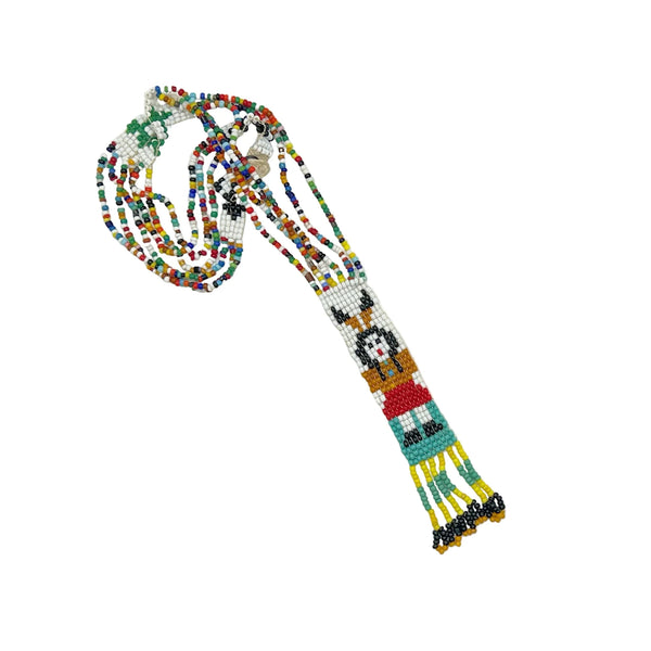 This striking Native American beaded necklace features a beautifully detailed figure adorned with two feathers in flowing black hair, dressed in a brown tunic and red skirt with black shoes. The design showcases a white upper background that transitions to a vibrant turquoise-teal green below, creating visual depth and interest. 