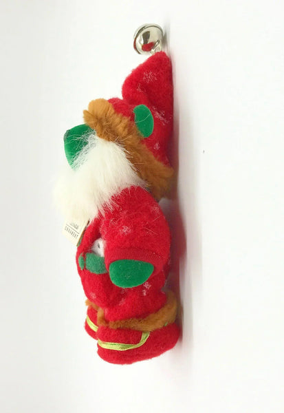 A small plush Christmas gnome ornament wearing a red outfit with green accents, a white beard, and a brown hat.