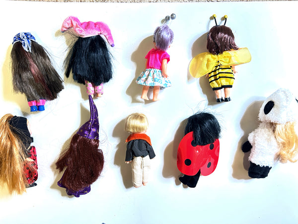 A collection of nine vintage Mattel Barbie Kelly Club 4-inch miniature dolls shown from the back against a white background. The assortment features dolls in various costumes and outfits, including a red-and-black spotted ladybug, a yellow-and-black striped bumblebee with wings, a plush white panda suit, a doll wearing a pink top and patterned blue skirt, and several figures with colorful hair and long wizard or witch hats