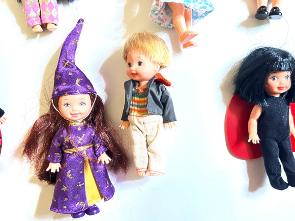 A group of five vintage 4-inch Mattel Barbie Kelly Club dolls in various outfits, including a doll in a bee costume, one in a sheep costume, a dark-haired doll wearing a black bodysuit with a red cape, a blonde boy doll in a grey jacket, and a doll in a pink shirt with a blue patterned skirt