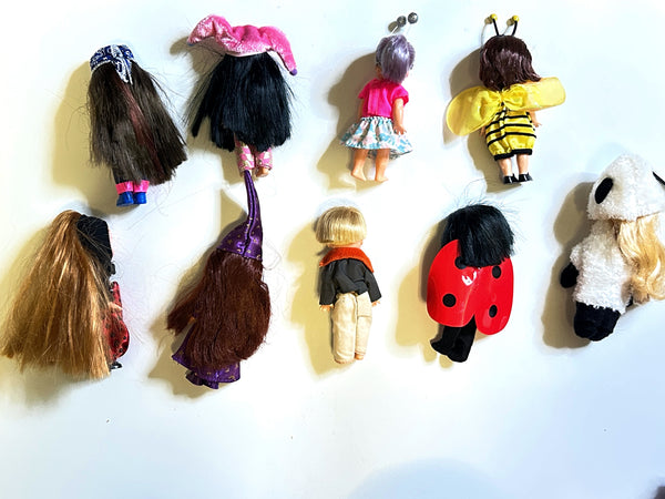A collection of nine vintage Mattel Barbie Kelly Club 4-inch miniature dolls shown from the back against a white background. The assortment features dolls in various costumes and outfits, including a red-and-black spotted ladybug, a yellow-and-black striped bumblebee with wings, a plush white panda suit, a doll wearing a pink top and patterned blue skirt, and several figures with colorful hair and long wizard or witch hats