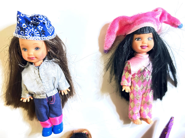 Two vintage 4-inch Mattel Kelly Club dolls. One wears a blue bandana and silver jacket; the other wears a pink jester hat and pink-and-gold patterned outfit