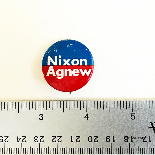 Vintage Nixon Agnew button with a ruler for scale on a white background