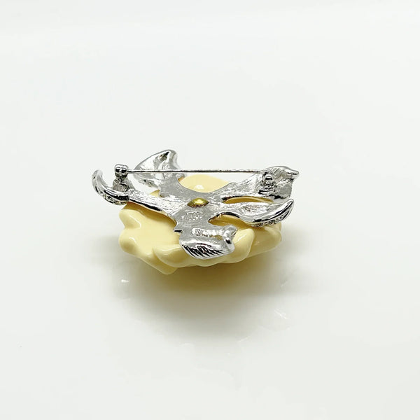 Vintage Nolan Miller Lara camellia flower brooch featuring carved cream lucite petals, a central clear rhinestone cluster, and textured silver-tone metal leaves
