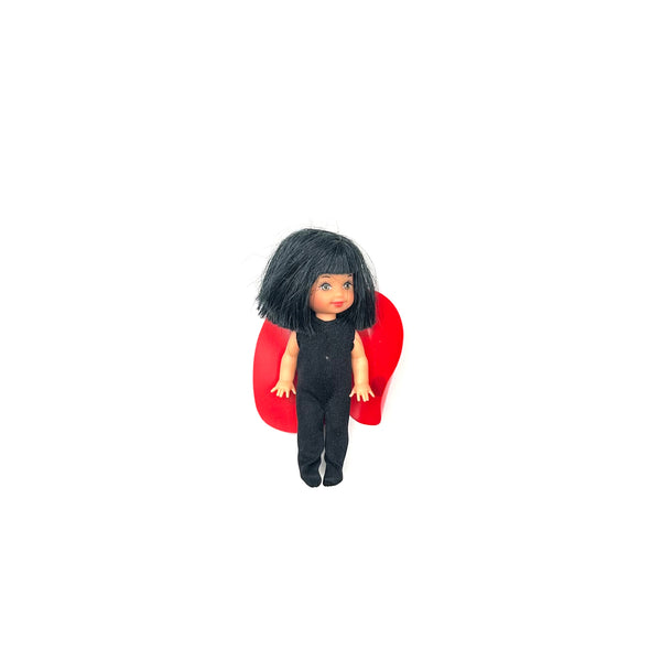 Vintage Mattel Barbie Kelly Club doll in Halloween costume with short black hair, wearing a black fringed top, matching pants, and a vibrant red plastic vampire or superhero cape against a solid white background