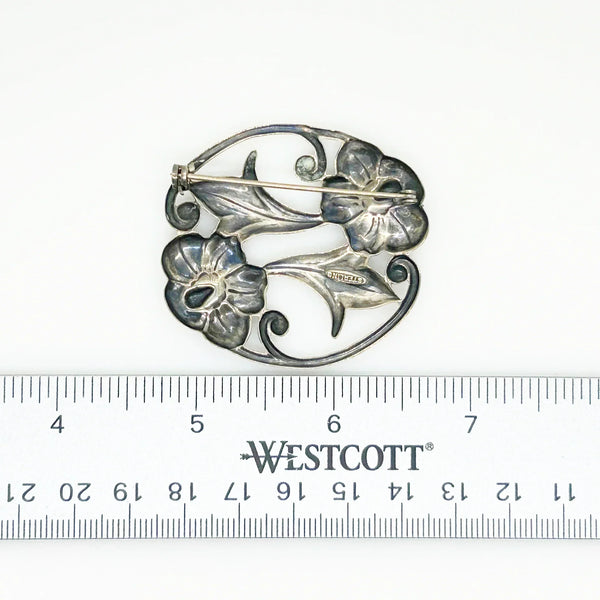 This stunning Art Nouveau floral brooch captivates with two beautiful blooms in an elegant oval shape. 