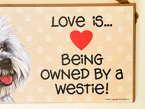 Showcase your love for Westies with this charming, decorative wooden hanging sign. The sign features the heartwarming phrase "Love is... Being Owned by a Westie" and depicts a delightful West Highland White Terrier. 