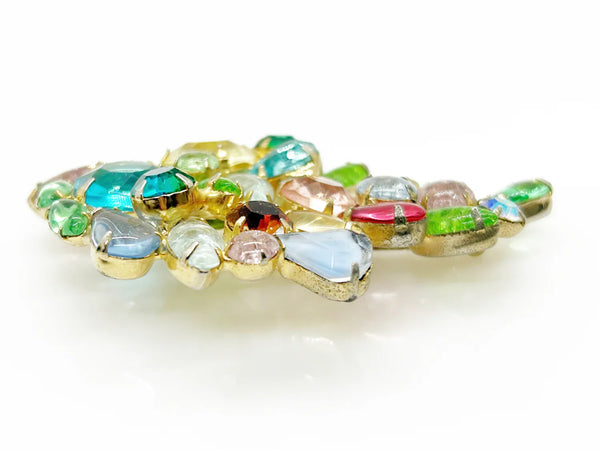 This gorgeous vintage brooch features a multicolored array of stones, including aqua, pale gold, shades of green, pink, and blue in round, marquise, and pear shapes.