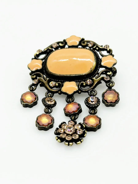 Level up your vintage jewelry collection with this stunning coral-hued brooch that captures timeless elegance. The piece showcases a luminous pale melon-orange centerstone framed by delicate star-shaped accents and peachy rhinestones that catch the light beautifully.