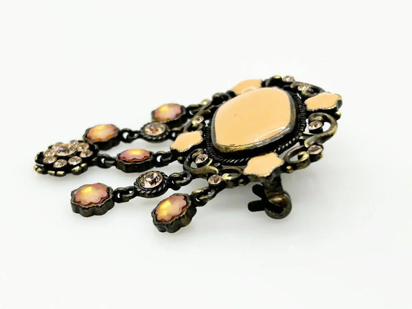 Level up your vintage jewelry collection with this stunning coral-hued brooch that captures timeless elegance. The piece showcases a luminous pale melon-orange centerstone framed by delicate star-shaped accents and peachy rhinestones that catch the light beautifully.