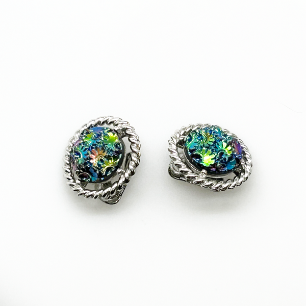 Discover the captivating allure of these authentic Sarah Coventry "Northern Lights" clip-on earrings, a stunning find from the 1960s-70s era. The dichroic glass centers showcase an extraordinary color-shifting quality that transforms from blue to green to purple to red as light dances across the surface—creating a mesmerizing effect that draws admiration from every angle.