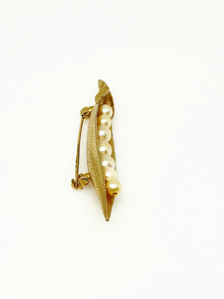 This vintage-inspired brooch features a brushed gold finish and showcases seven delicately graduated faux pearls, measuring 2.75 inches in length.