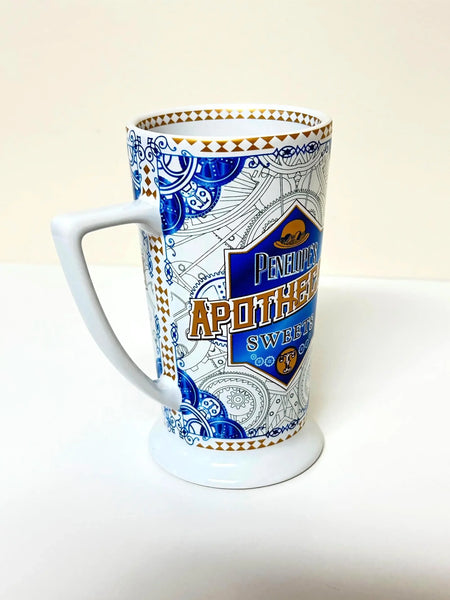 Universal Studios Toothsome Chocolate Emporium Penelope's Apothecary Sweets tall ceramic pedestal mug with blue, white, and gold geometric pattern on a solid white background.