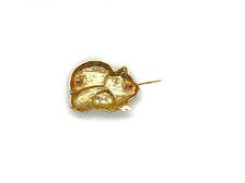 A vintage DKI gold-tone enamel brooch shaped like two snuggling black and white spotted pigs on a white background.