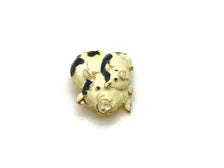 A vintage DKI gold-tone enamel brooch shaped like two snuggling black and white spotted pigs on a white background.