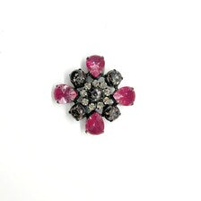 Vintage costume jewelry brooch pin featuring a central rhinestone cluster encircled by a halo of clear crystals, with alternating pear-cut pink faux rubies and round faceted gunmetal black stones in a dark metallic prong setting.
