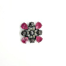 Vintage costume jewelry brooch pin featuring a central rhinestone cluster encircled by a halo of clear crystals, with alternating pear-cut pink faux rubies and round faceted gunmetal black stones in a dark metallic prong setting.