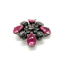 Vintage costume jewelry brooch pin featuring a central rhinestone cluster encircled by a halo of clear crystals, with alternating pear-cut pink faux rubies and round faceted gunmetal black stones in a dark metallic prong setting.