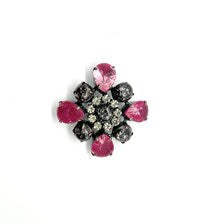 Vintage costume jewelry brooch pin featuring a central rhinestone cluster encircled by a halo of clear crystals, with alternating pear-cut pink faux rubies and round faceted gunmetal black stones in a dark metallic prong setting.