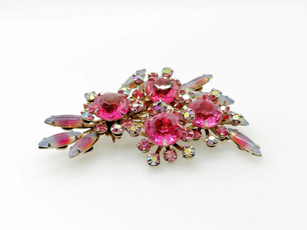 Add a touch of unique style and vibrance to any outfit with this stunning vintage pink brooch. Featuring a captivating design of four layers and various shades of pink stones, including a vibrant round faceted pink stone at the center of each section. It is surrounded by round pink iridescent and vivid stones, as well as several striped watermelon marquise cabochon stones for a unique finishing touch.