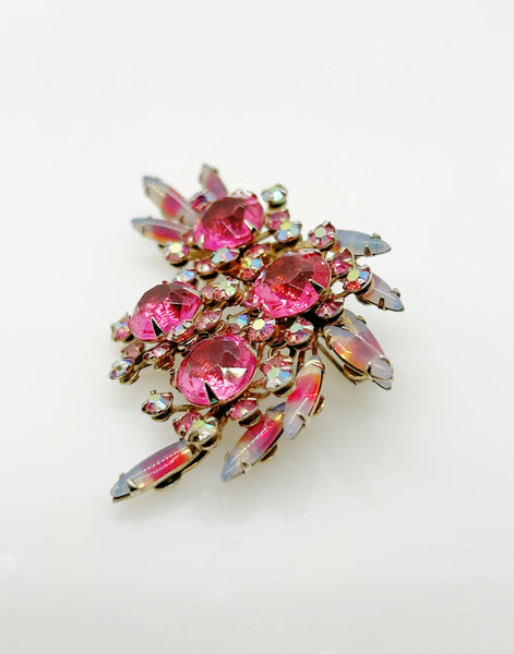 Add a touch of unique style and vibrance to any outfit with this stunning vintage pink brooch. Featuring a captivating design of four layers and various shades of pink stones, including a vibrant round faceted pink stone at the center of each section. It is surrounded by round pink iridescent and vivid stones, as well as several striped watermelon marquise cabochon stones for a unique finishing touch.