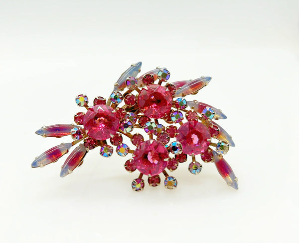 Add a touch of unique style and vibrance to any outfit with this stunning vintage pink brooch. Featuring a captivating design of four layers and various shades of pink stones, including a vibrant round faceted pink stone at the center of each section. It is surrounded by round pink iridescent and vivid stones, as well as several striped watermelon marquise cabochon stones for a unique finishing touch.