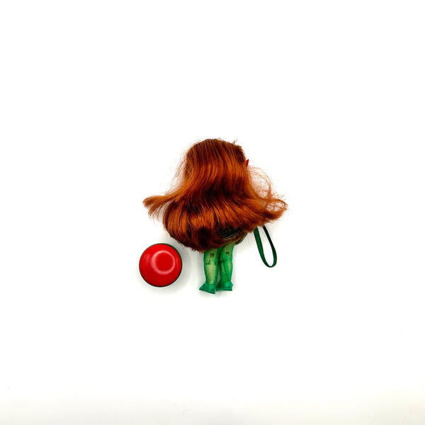 Rear view of a vintage 2001 Mattel Kelly Club Poinsettia Jenny holiday Christmas tree ornament doll, showcasing auburn doll hair, green sparkly tights, and a red ball ornament accessory for collectors