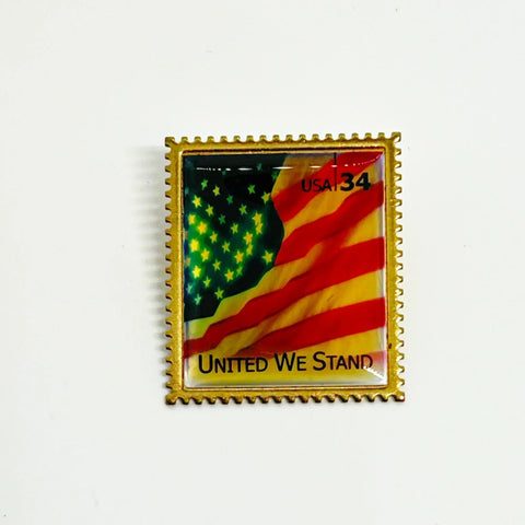 Pin with American flag design and 'United We Stand' text on a white background