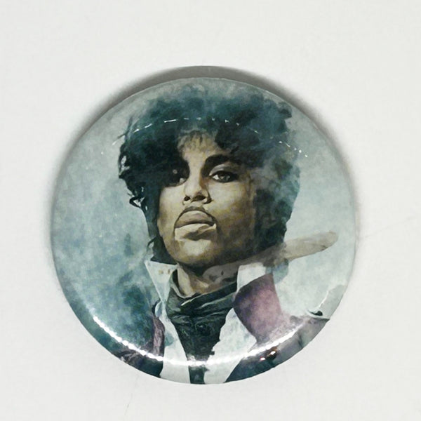 A vintage 1984 Prince pinback button badge featuring a painted portrait of Prince Rogers Nelson during the Purple Rain era