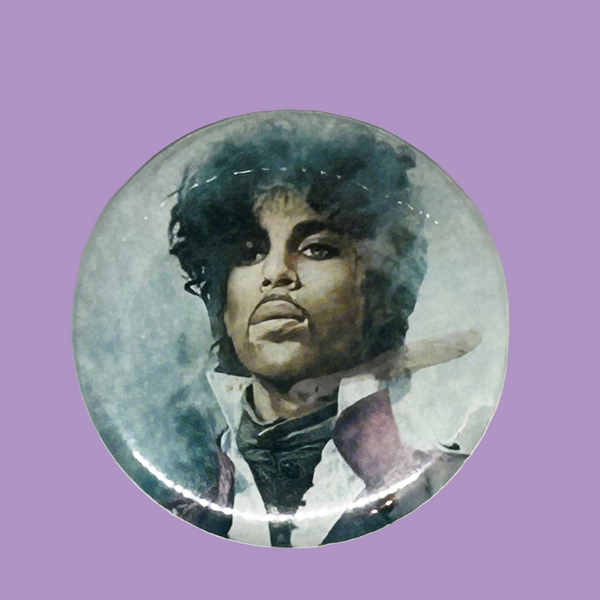 A vintage 1984 Prince pinback button badge featuring a painted portrait of Prince Rogers Nelson during the Purple Rain era