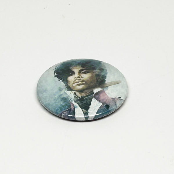 A vintage 1984 Prince pinback button badge featuring a painted portrait of Prince Rogers Nelson during the Purple Rain era